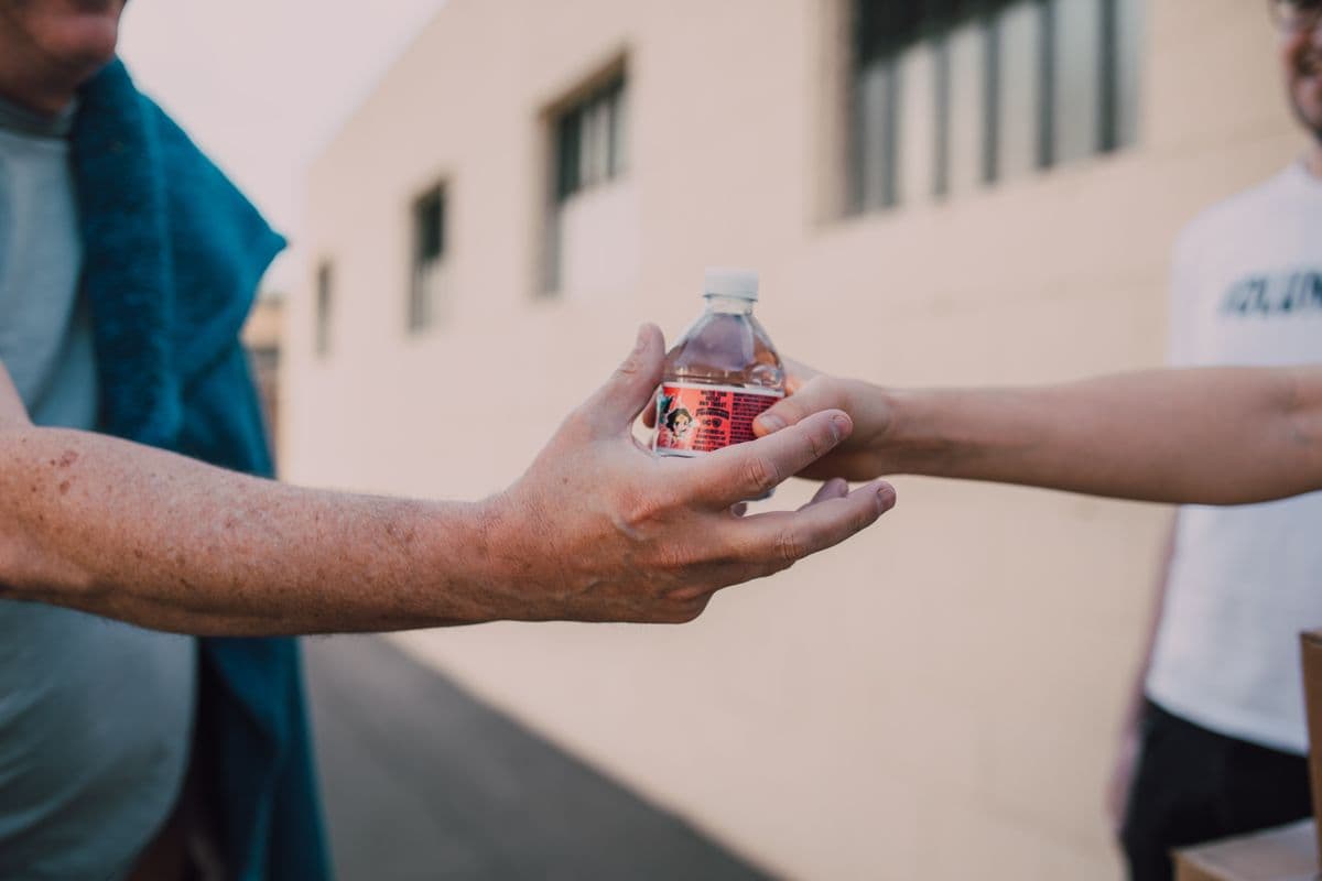 One person handing a bottle of water to another.