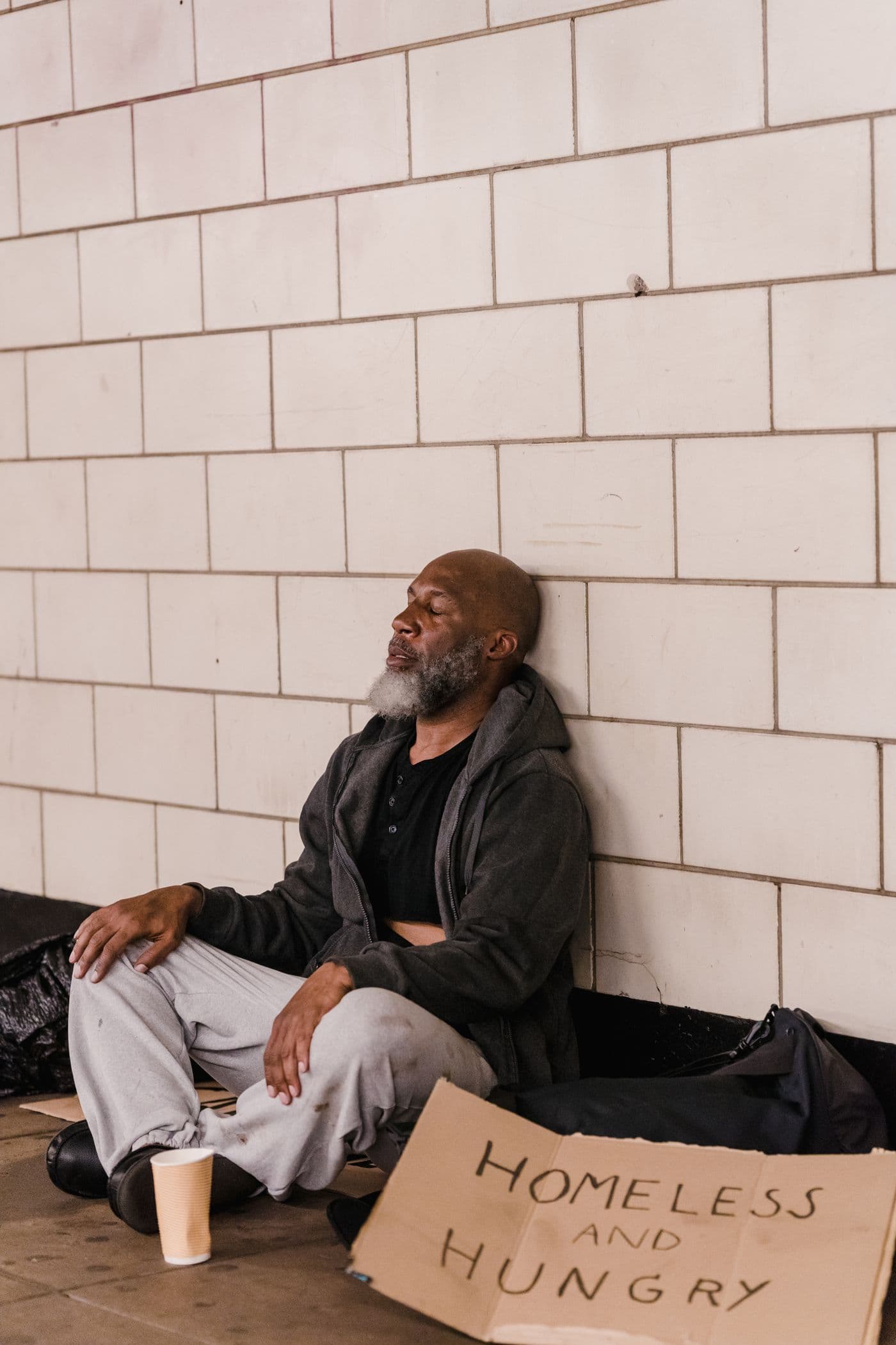 A man sitting against a wall on a city street.