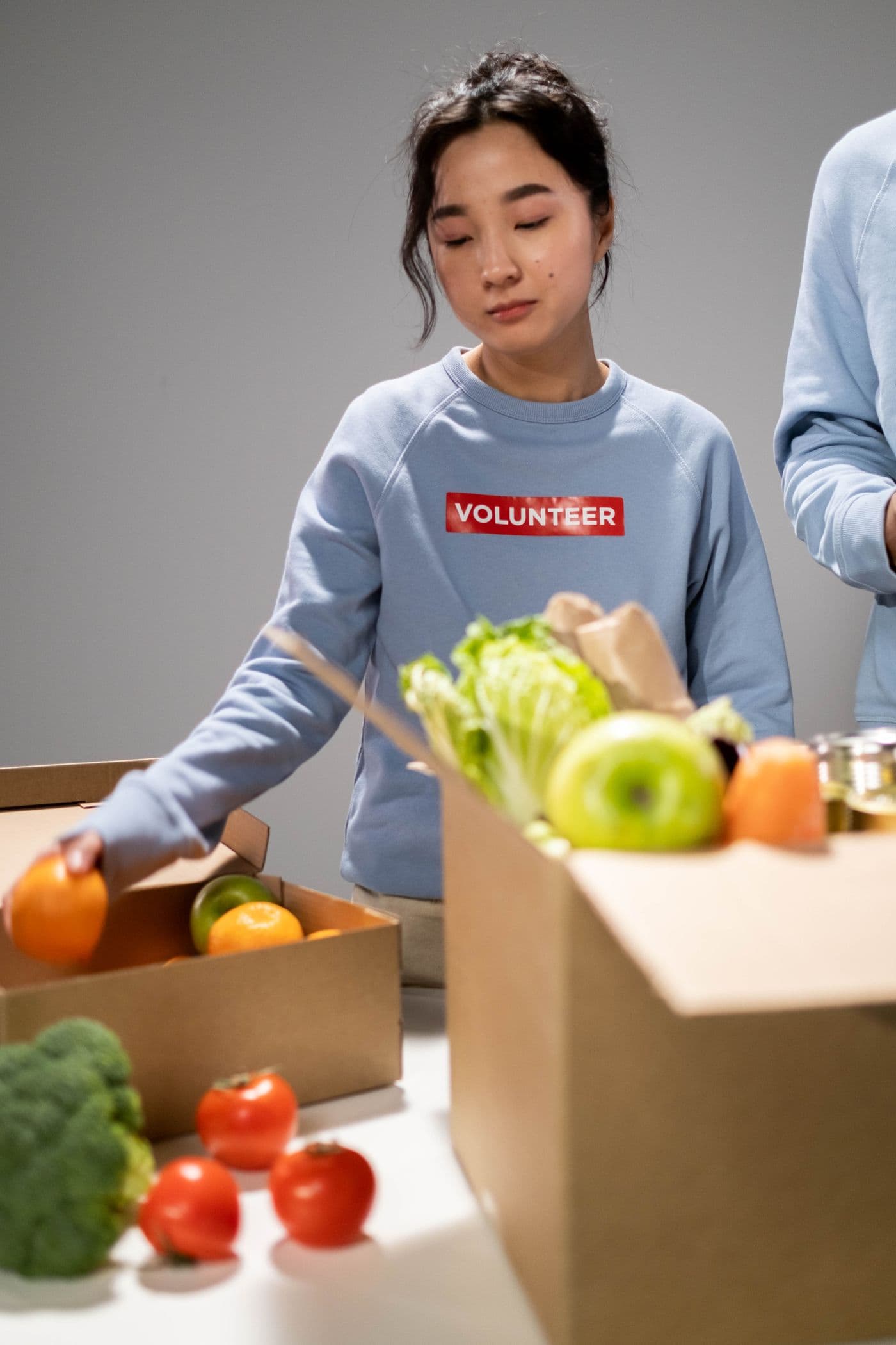 A volunteer packing a box of fresh produce.