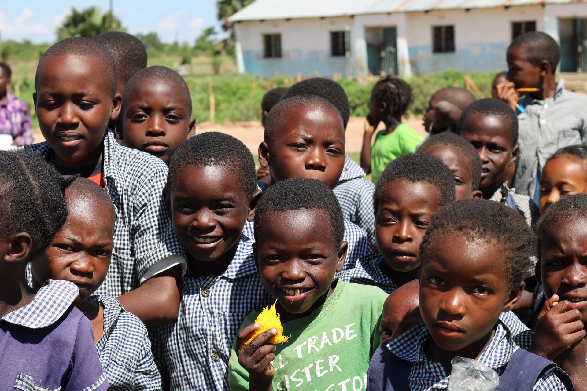 A group of schoolchildren smiling together in a schoolyard.
