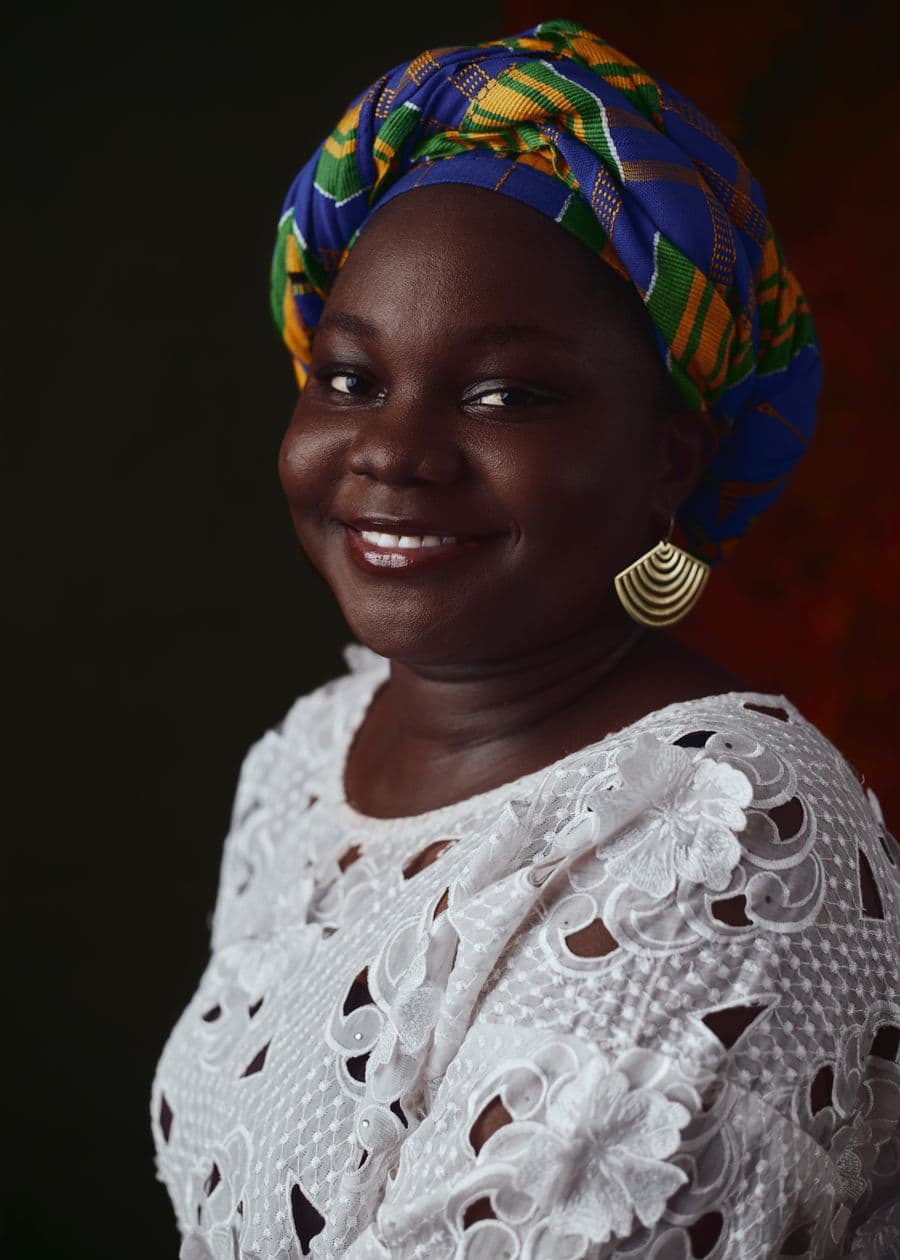 Portrait of a smiling woman in a patterned headwrap.