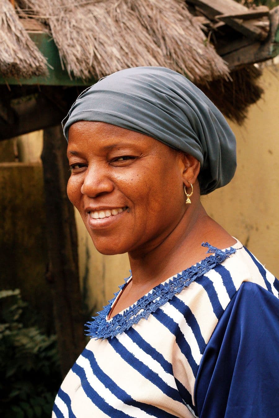 Portrait of a smiling woman wearing a grey headwrap.