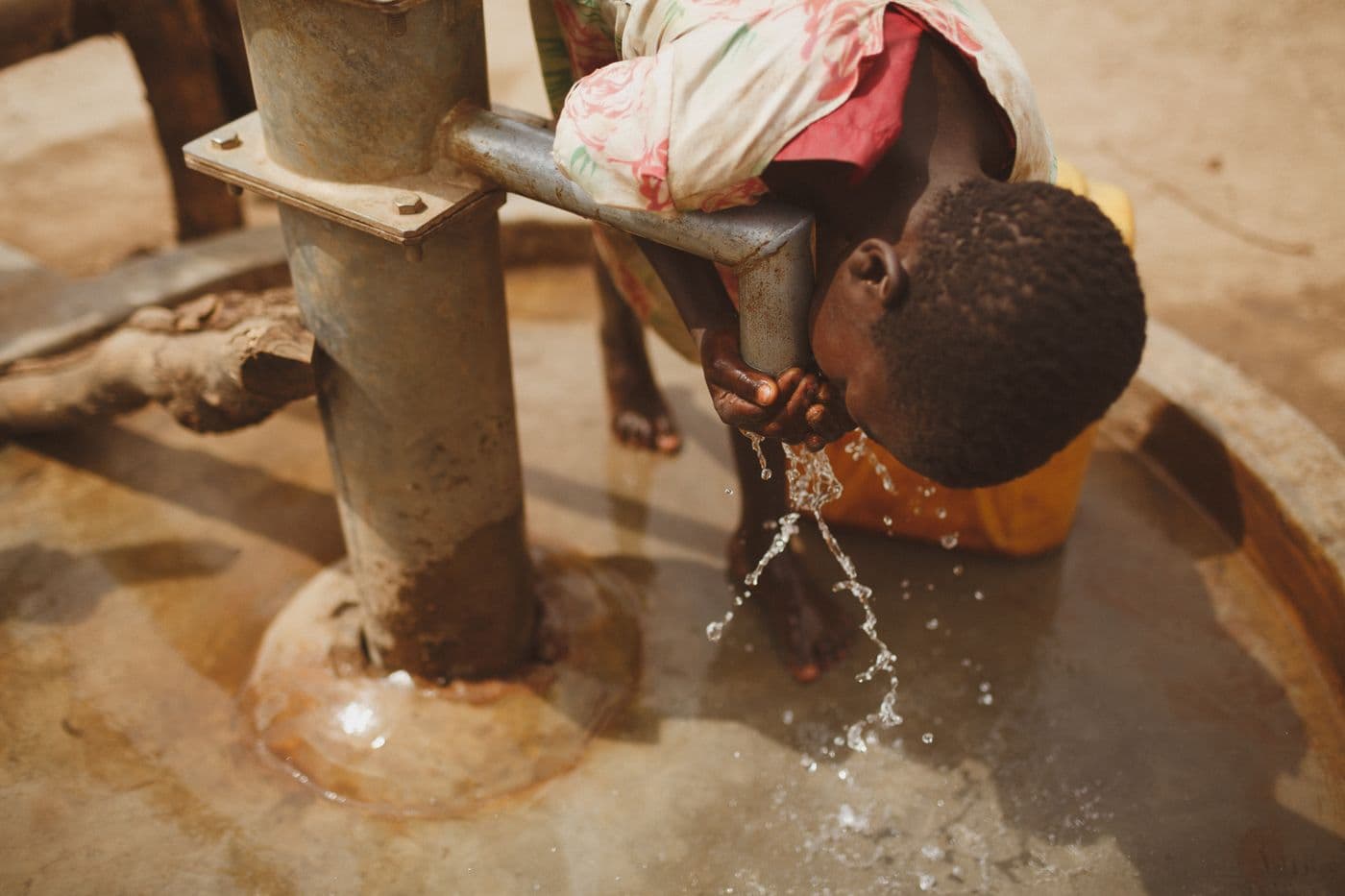 A child drinking clean water from a village well.